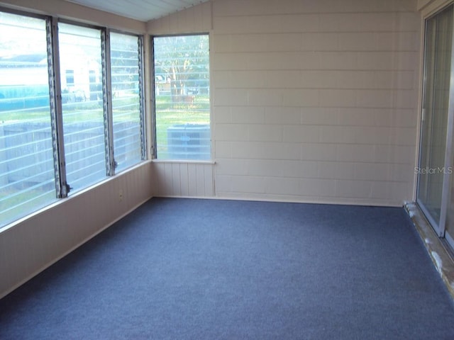 unfurnished room with dark colored carpet and vaulted ceiling