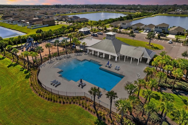 pool at dusk with a water view and a patio area