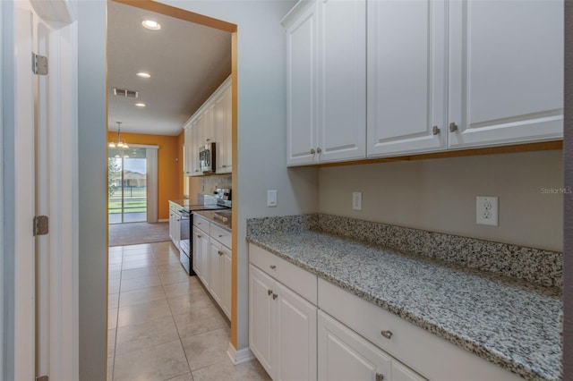 kitchen featuring light stone countertops, a chandelier, light tile patterned floors, white cabinets, and stainless steel appliances