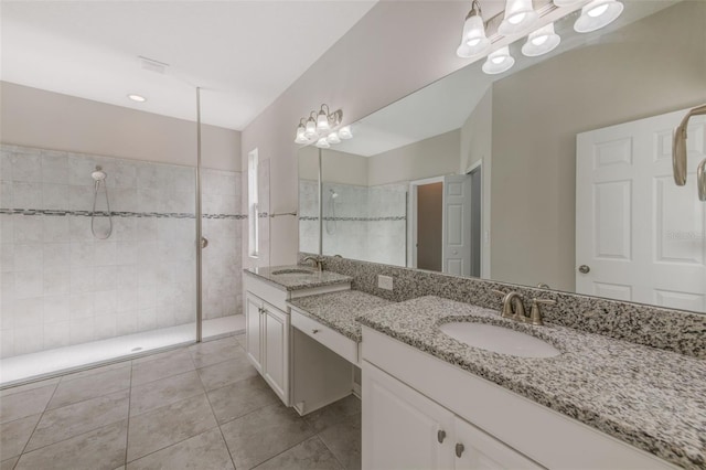 bathroom with tile patterned floors, vanity, and a tile shower