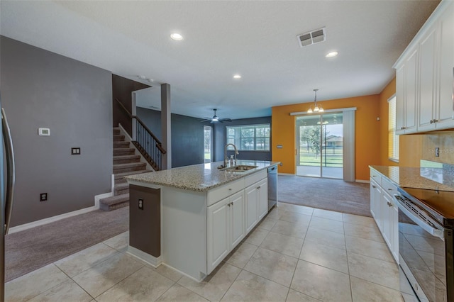 kitchen with light carpet, ceiling fan with notable chandelier, a kitchen island with sink, and stainless steel appliances