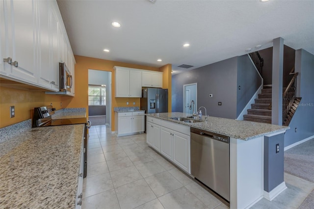 kitchen with appliances with stainless steel finishes, sink, white cabinets, light tile patterned floors, and a kitchen island with sink