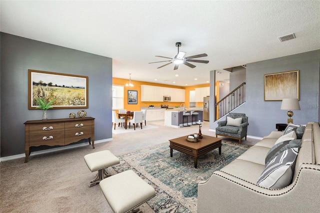 carpeted living room with a textured ceiling and ceiling fan