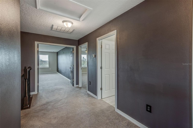 hall with a textured ceiling and light carpet