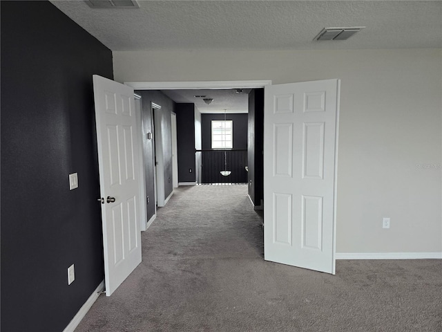 corridor with carpet flooring and a textured ceiling