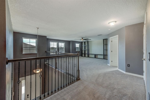 hall with a textured ceiling and carpet flooring