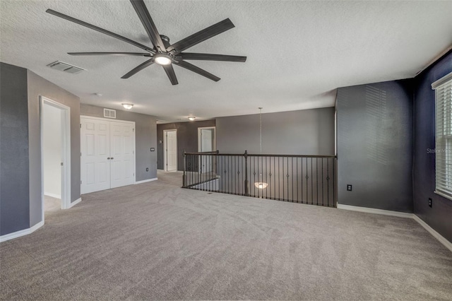 carpeted spare room with ceiling fan and a textured ceiling