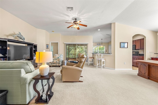 living room featuring lofted ceiling, ceiling fan, and light colored carpet