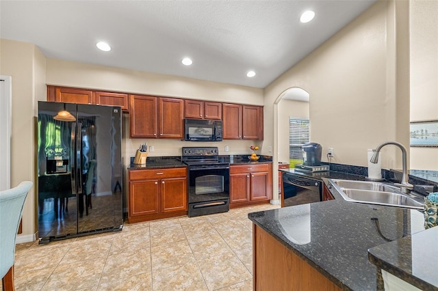 kitchen with dark stone counters, black appliances, light tile patterned floors, and sink