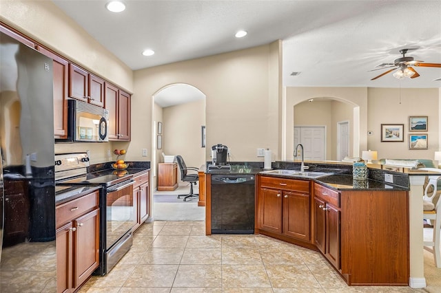 kitchen featuring ceiling fan, light tile patterned floors, sink, appliances with stainless steel finishes, and dark stone countertops