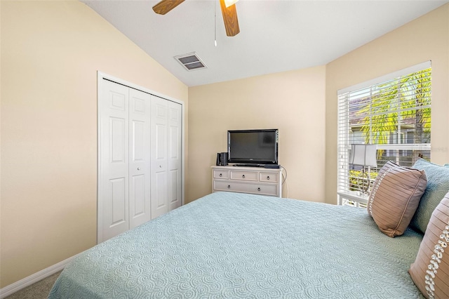 carpeted bedroom with ceiling fan, a closet, and vaulted ceiling