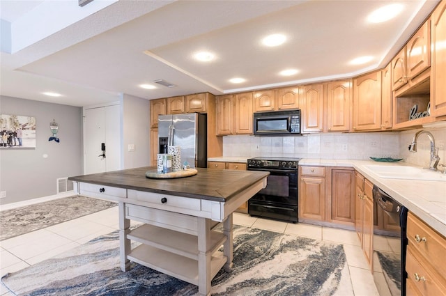 kitchen featuring tile counters, light tile patterned flooring, sink, decorative backsplash, and black appliances