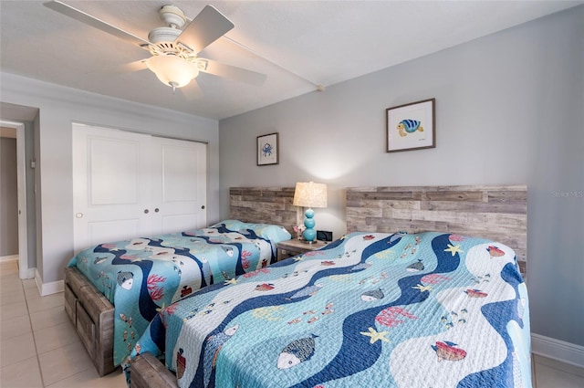 tiled bedroom featuring ceiling fan and a closet