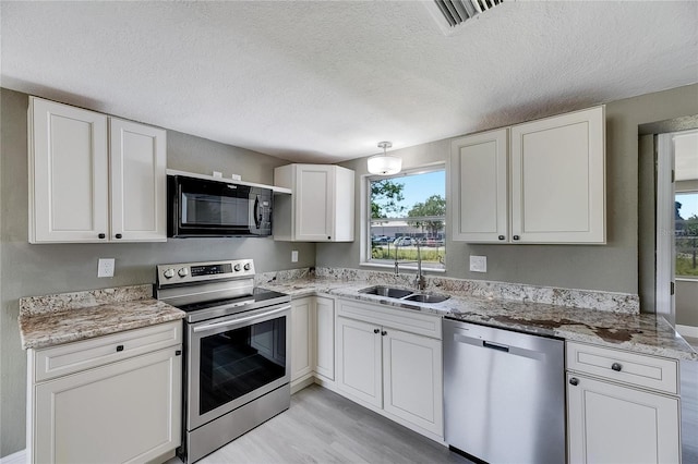 kitchen with light hardwood / wood-style flooring, white cabinetry, appliances with stainless steel finishes, and sink