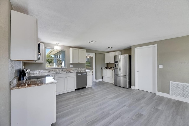 kitchen with light wood-type flooring, white cabinetry, appliances with stainless steel finishes, and sink