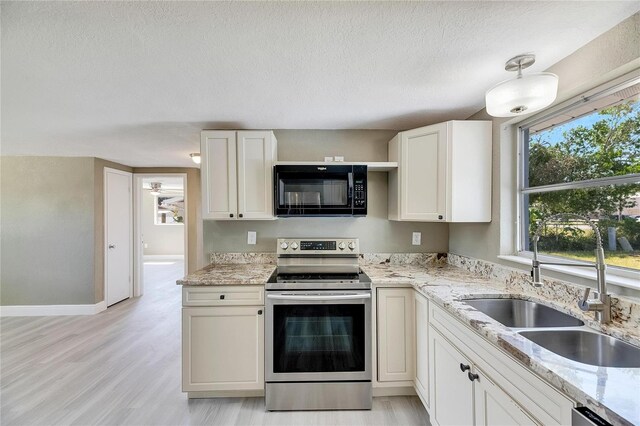 kitchen featuring white cabinets, sink, a textured ceiling, light hardwood / wood-style flooring, and stainless steel appliances