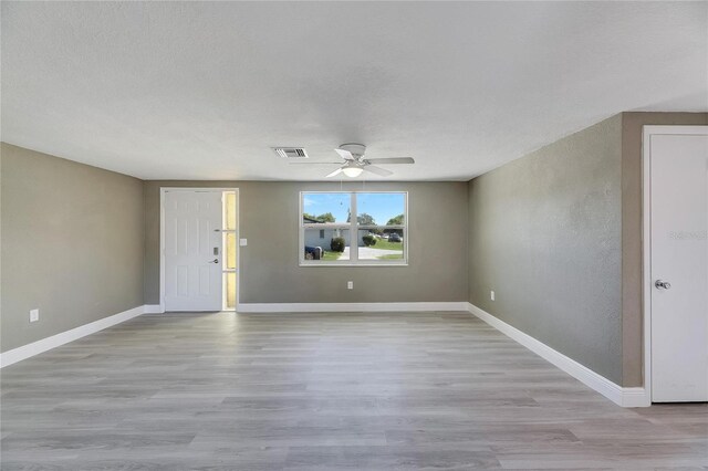 empty room with a textured ceiling, ceiling fan, and light hardwood / wood-style flooring