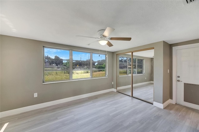 unfurnished bedroom with a closet, light hardwood / wood-style floors, ceiling fan, and a textured ceiling