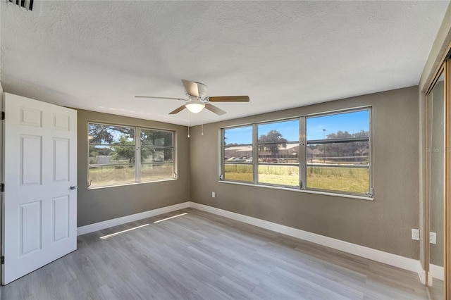 unfurnished room with ceiling fan, hardwood / wood-style flooring, and a textured ceiling