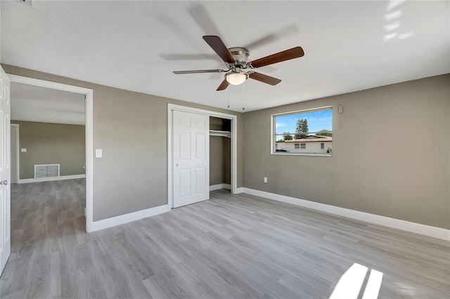 unfurnished bedroom featuring a closet, light wood-type flooring, ceiling fan, and a textured ceiling