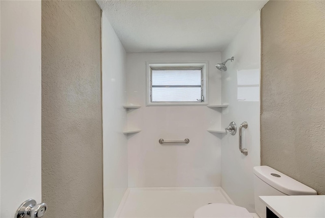 bathroom with a textured ceiling, walk in shower, vanity, and toilet