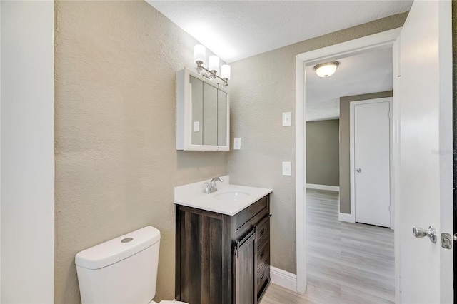 bathroom featuring a textured ceiling, vanity, toilet, and hardwood / wood-style flooring