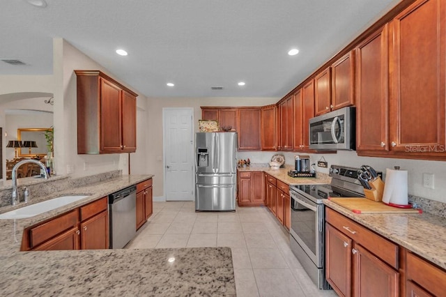 kitchen featuring light stone counters, sink, appliances with stainless steel finishes, and light tile patterned floors