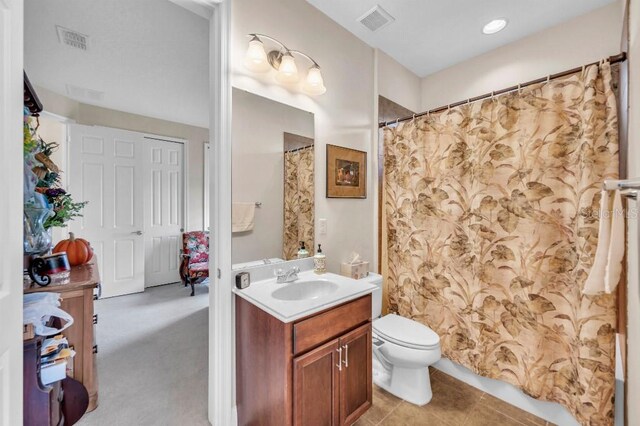 bathroom featuring tile patterned flooring, curtained shower, vanity, and toilet