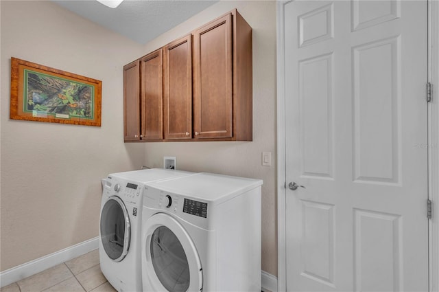 washroom featuring a textured ceiling, light tile patterned floors, washer and dryer, and cabinets