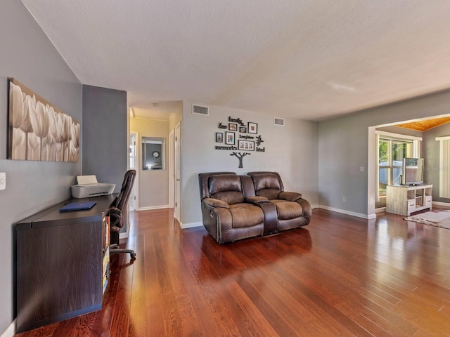 living room with a textured ceiling and dark hardwood / wood-style floors