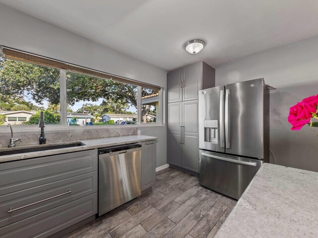 kitchen with gray cabinets, light wood-type flooring, and stainless steel appliances