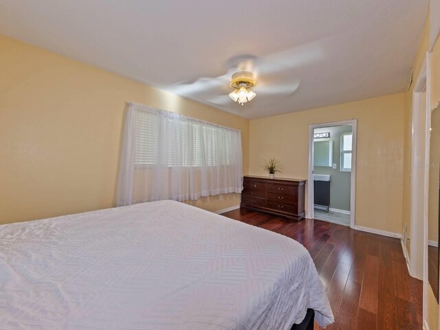 bedroom featuring ceiling fan, ensuite bath, and dark hardwood / wood-style flooring