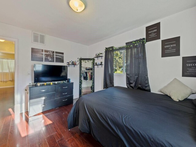 bedroom with ensuite bathroom and dark hardwood / wood-style flooring