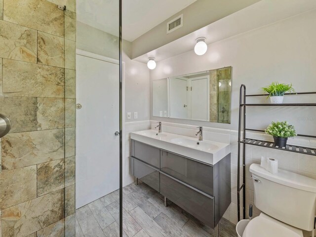 bathroom featuring tile walls, vanity, and toilet