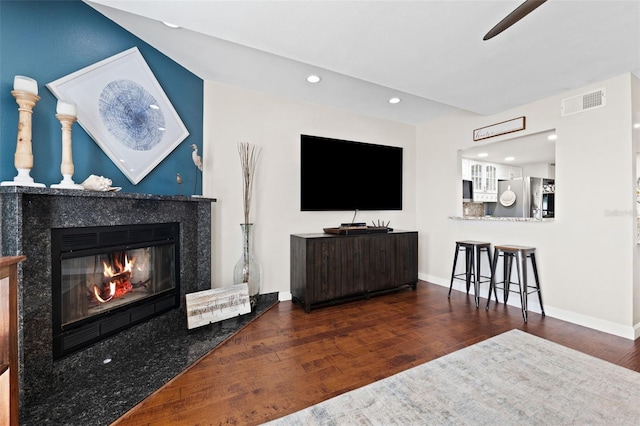 living room with dark hardwood / wood-style floors, ceiling fan, and a premium fireplace