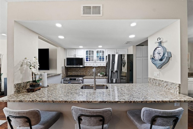 kitchen with appliances with stainless steel finishes, white cabinets, kitchen peninsula, dark hardwood / wood-style flooring, and sink