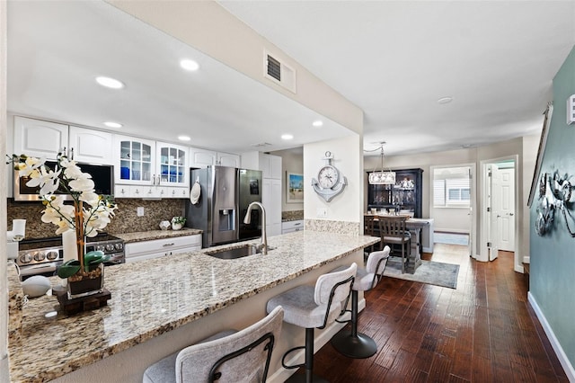 kitchen featuring white cabinets, tasteful backsplash, decorative light fixtures, dark wood-type flooring, and stainless steel appliances