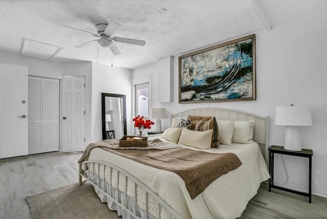 bedroom with a textured ceiling, light wood-type flooring, and ceiling fan