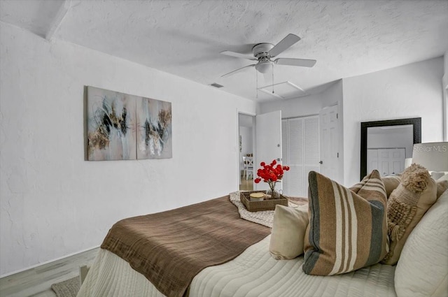 bedroom with hardwood / wood-style floors, ceiling fan, and a textured ceiling