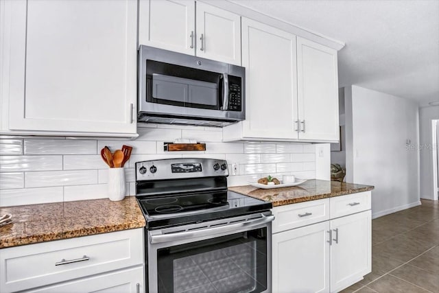 kitchen featuring backsplash, dark stone counters, tile patterned flooring, white cabinetry, and stainless steel appliances