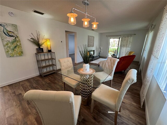 dining space with a textured ceiling, dark hardwood / wood-style flooring, and a notable chandelier