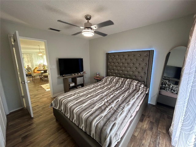 bedroom featuring a ceiling fan, a textured ceiling, visible vents, and dark wood-style flooring