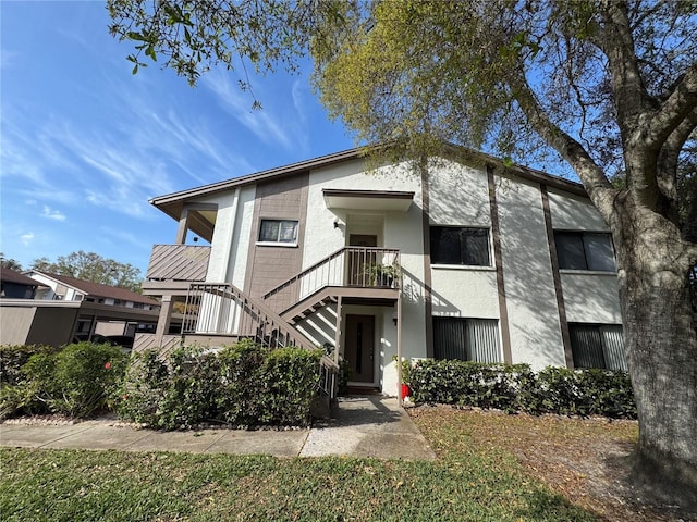 view of front facade featuring stairs and stucco siding