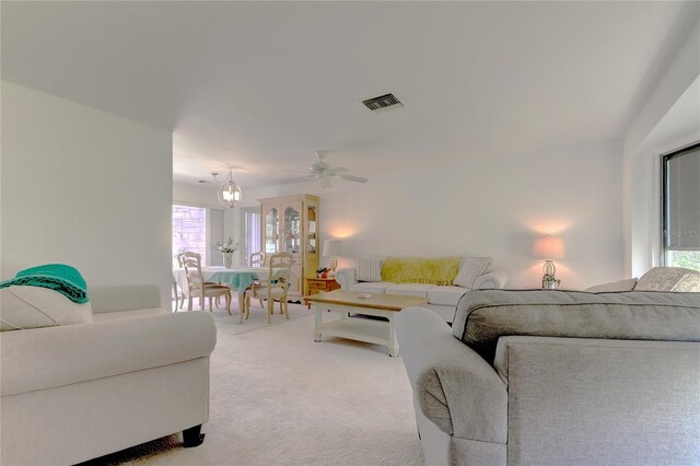 carpeted living room featuring ceiling fan with notable chandelier