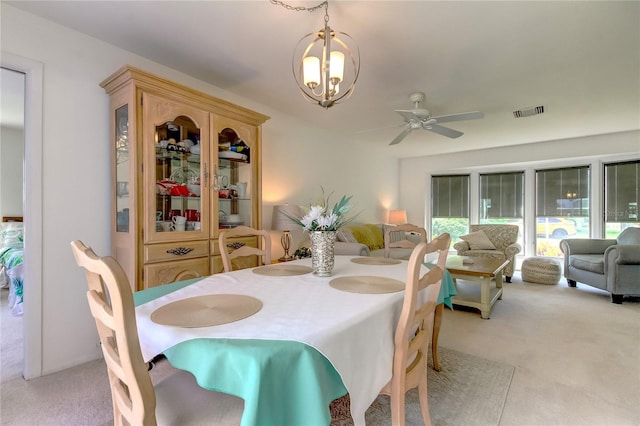 dining room featuring light carpet and ceiling fan with notable chandelier