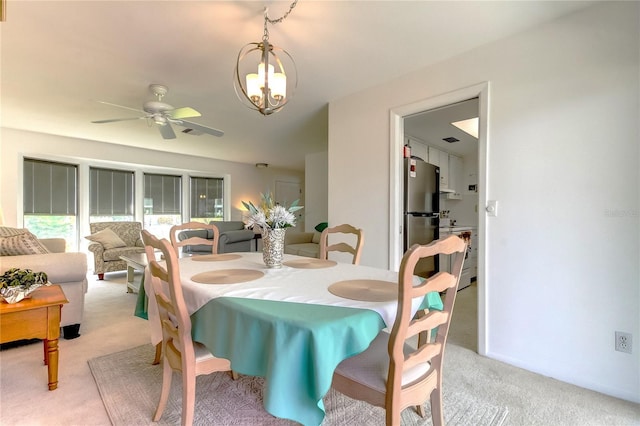 dining room featuring ceiling fan with notable chandelier and light carpet