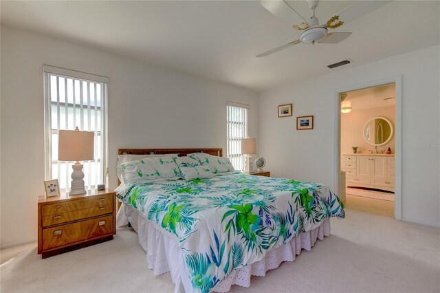 bedroom with light carpet, ensuite bath, and ceiling fan