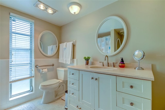 bathroom with tile walls, vanity, and toilet