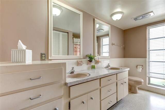 bathroom with vanity, tile walls, and toilet