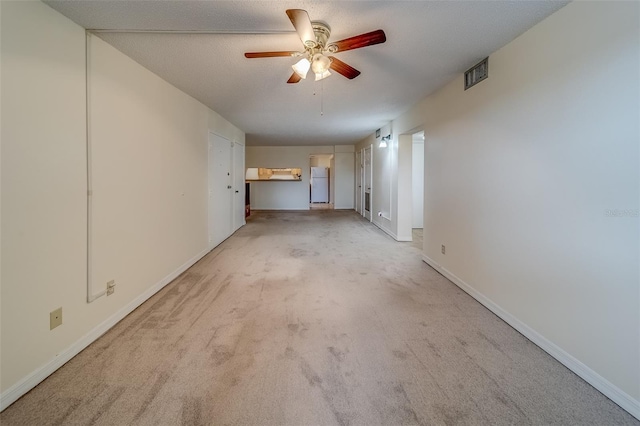 spare room with a textured ceiling, light carpet, and ceiling fan